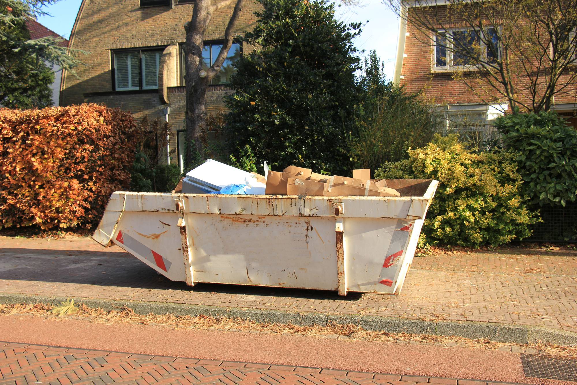 Bauschuttcontainer vor Wohnhaus mit Kartons